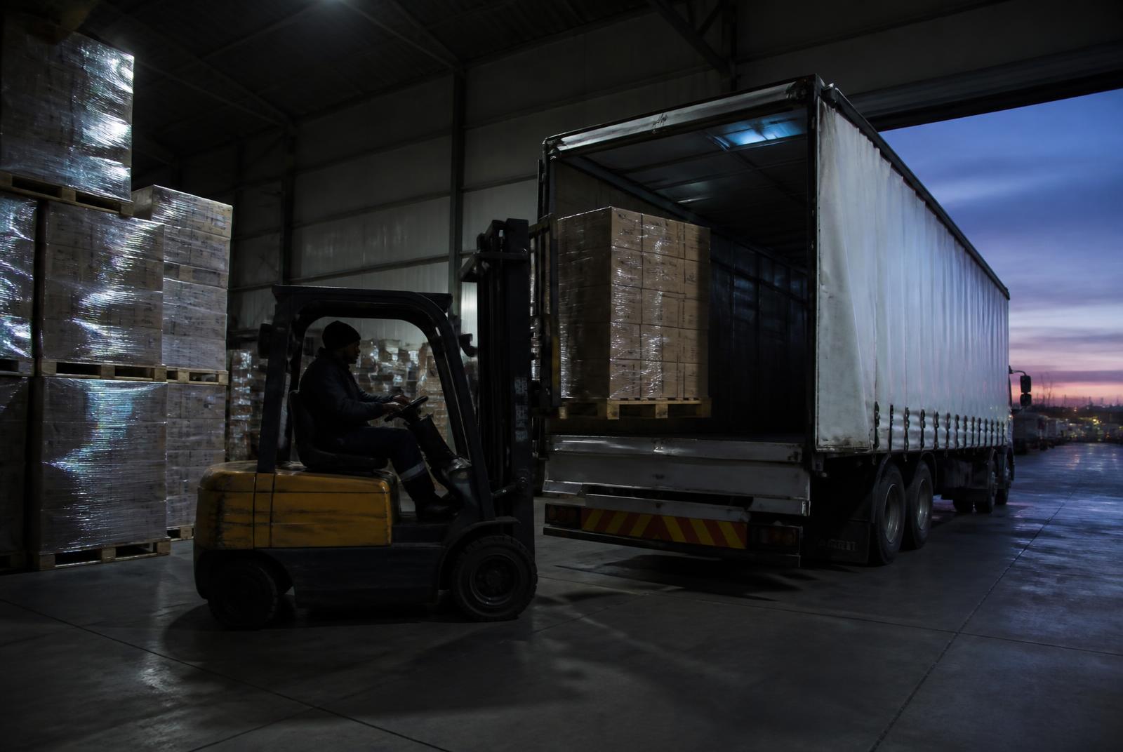 Pallets being loaded into a curtain-side truck at a distribution warehouse